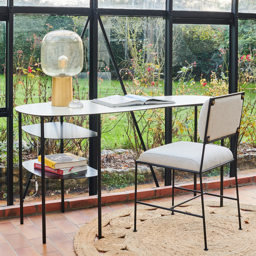 Bureau élégant en acier avec rangement intégrée, accompagné d'une chaise moderne, dans un cadre lumineux et verdoyant.