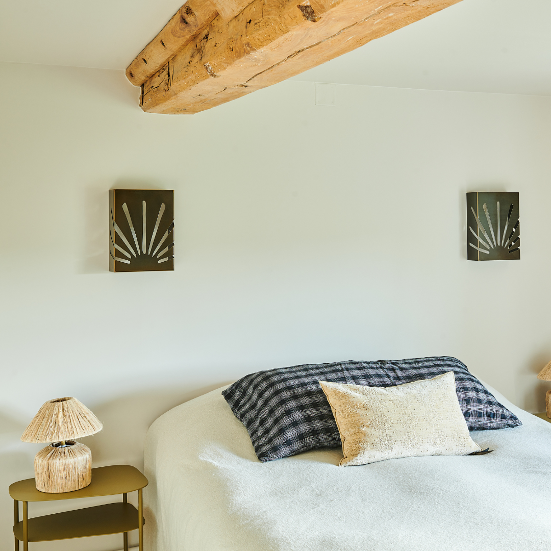 Éclairage mural en acier au design épuré dans une chambre moderne, avec lit et accessoires décoratifs.