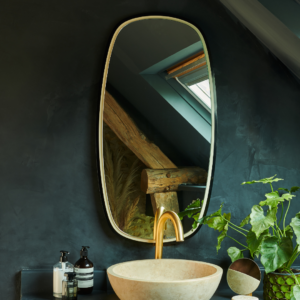 Miroir Héra ovale avec finition moderne, suspendu au-dessus d'un lavabo en pierre dans une salle de bain contemporaine.
