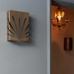 Applique en acier avec design moderne évoquant des rayons de soleil, accrochée sur un mur gris, éclairant un intérieur élégant.