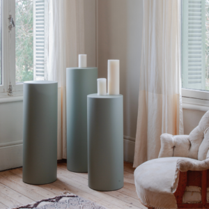 Stèle Aphrodite trio en acier, finition mate, avec bougies, dans un intérieur moderne lumineux et épuré.