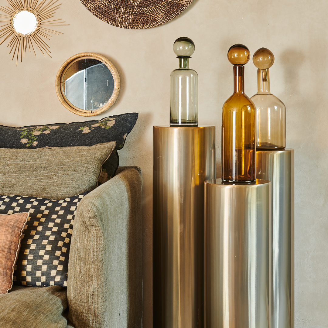 Stèle en acier doré avec trois bouteilles en verre, mise en scène dans un intérieur moderne et épuré.