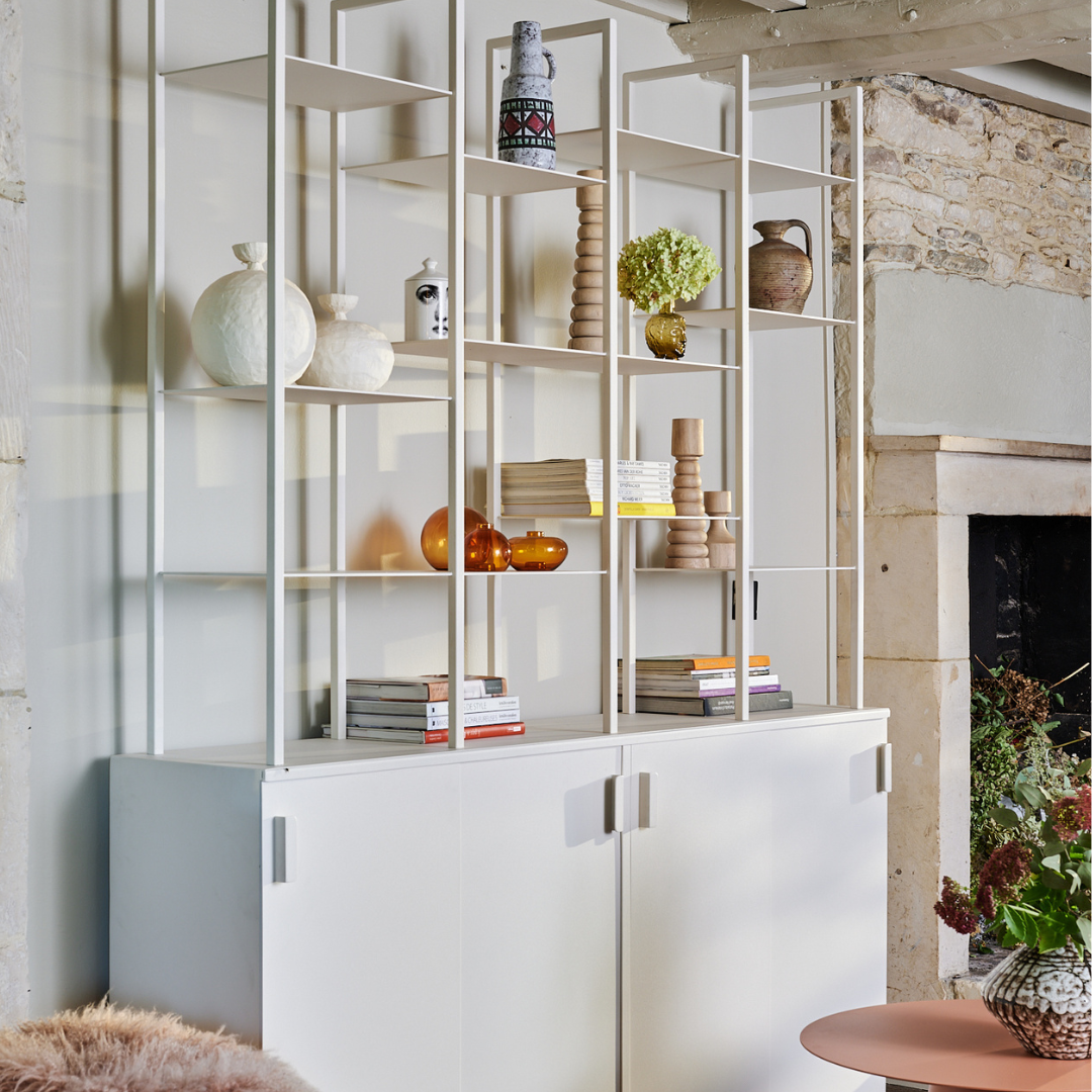 Étagère moderne en acier, finition épurée, présentant divers objets décoratifs, intégrée dans un intérieur contemporain.