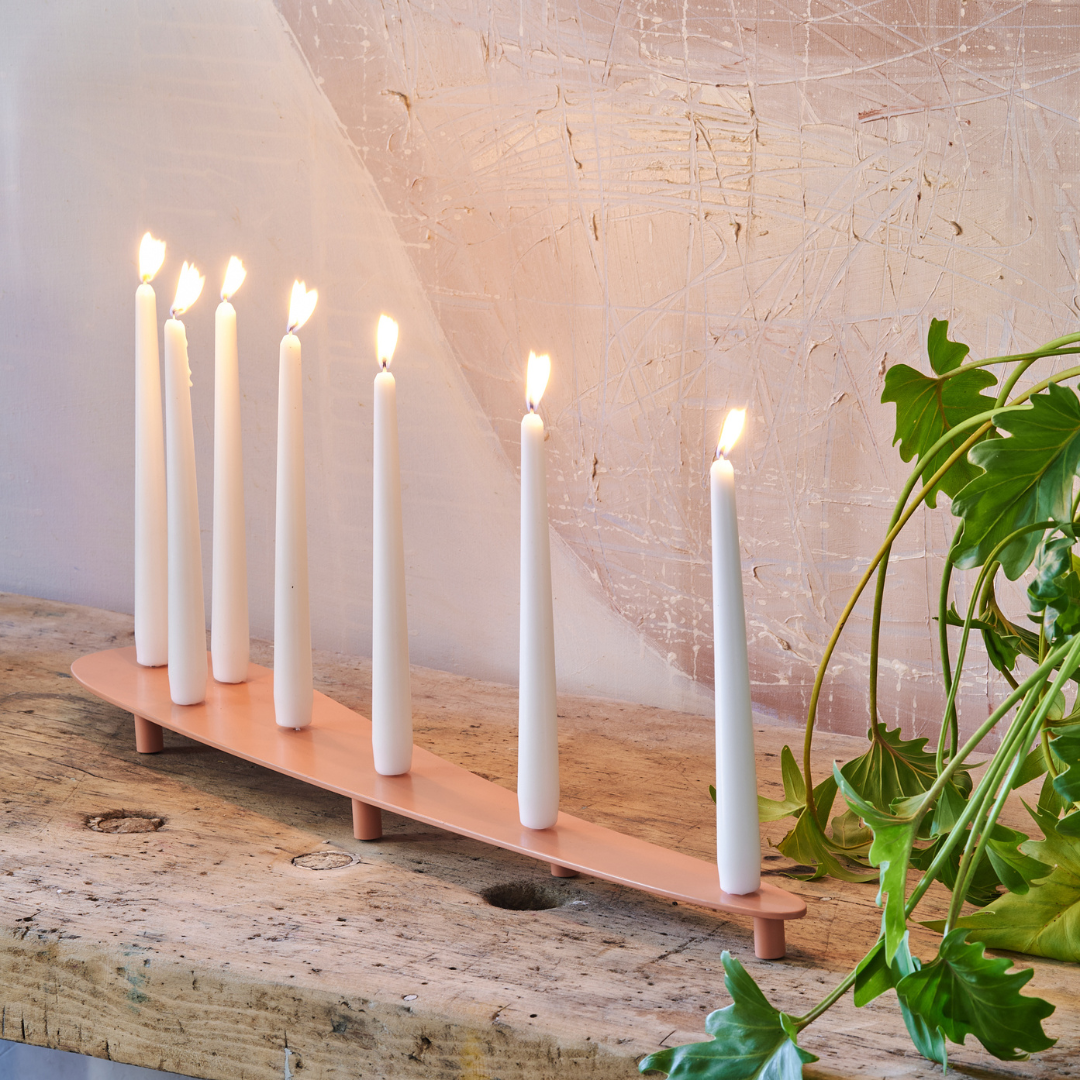 Bougeoir Aphrodite en acier, avec huit bougies blanches allumées, sur un support en beige, dans un intérieur moderne.