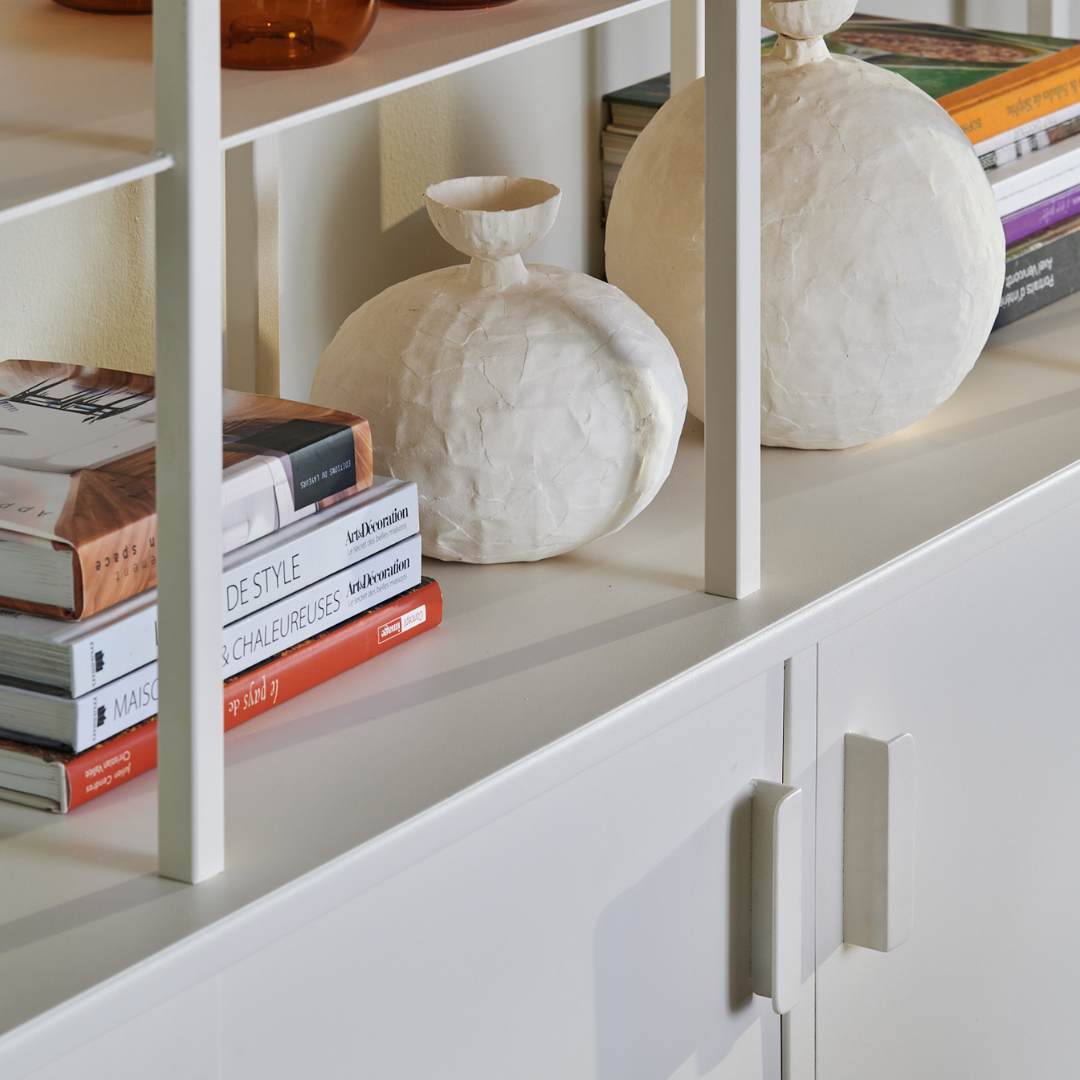 Étagère moderne avec livres et vases en papier, mettant en valeur un design épuré et contemporain.