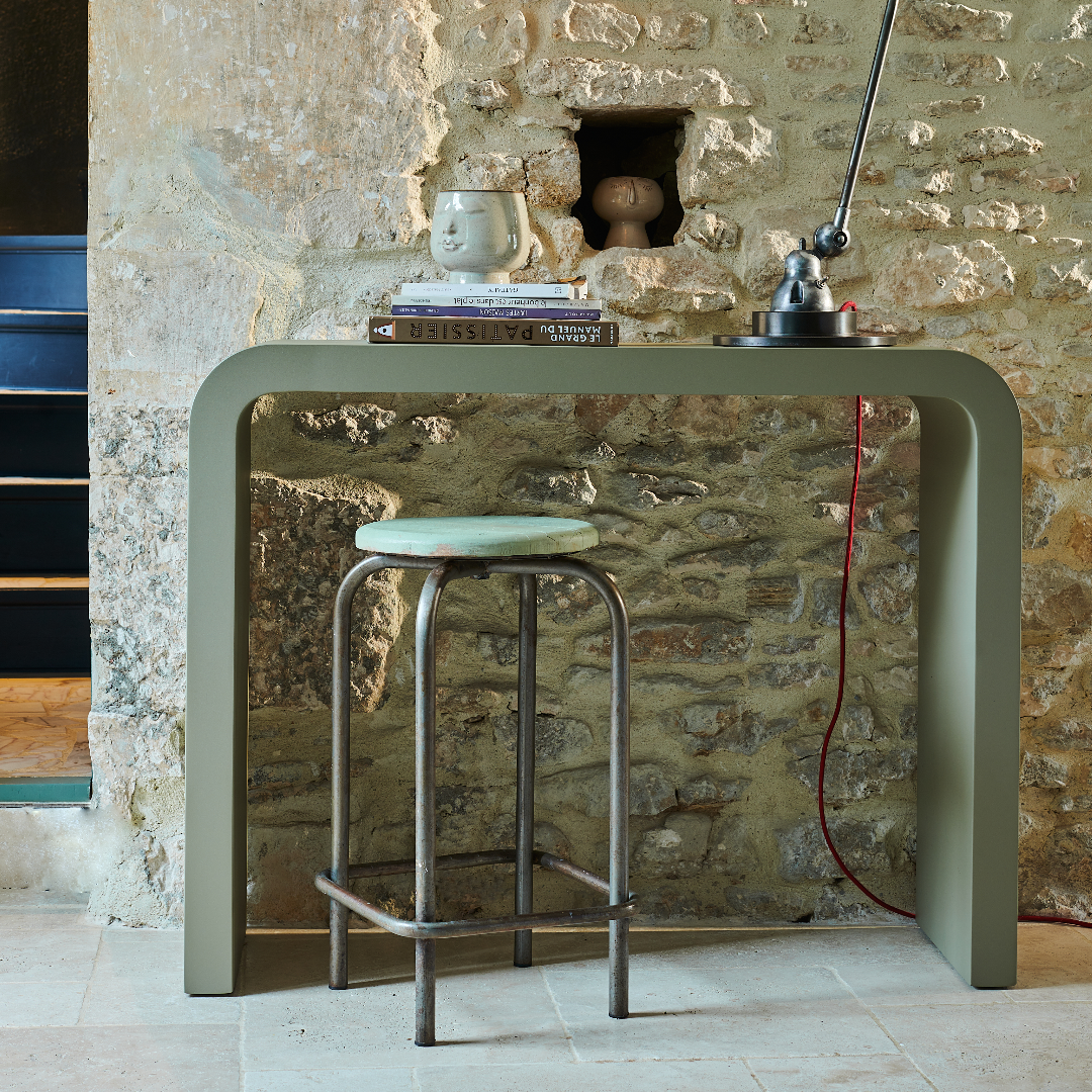 Table en acier au design épuré avec un tabouret vintage dans un intérieur moderne en pierre.