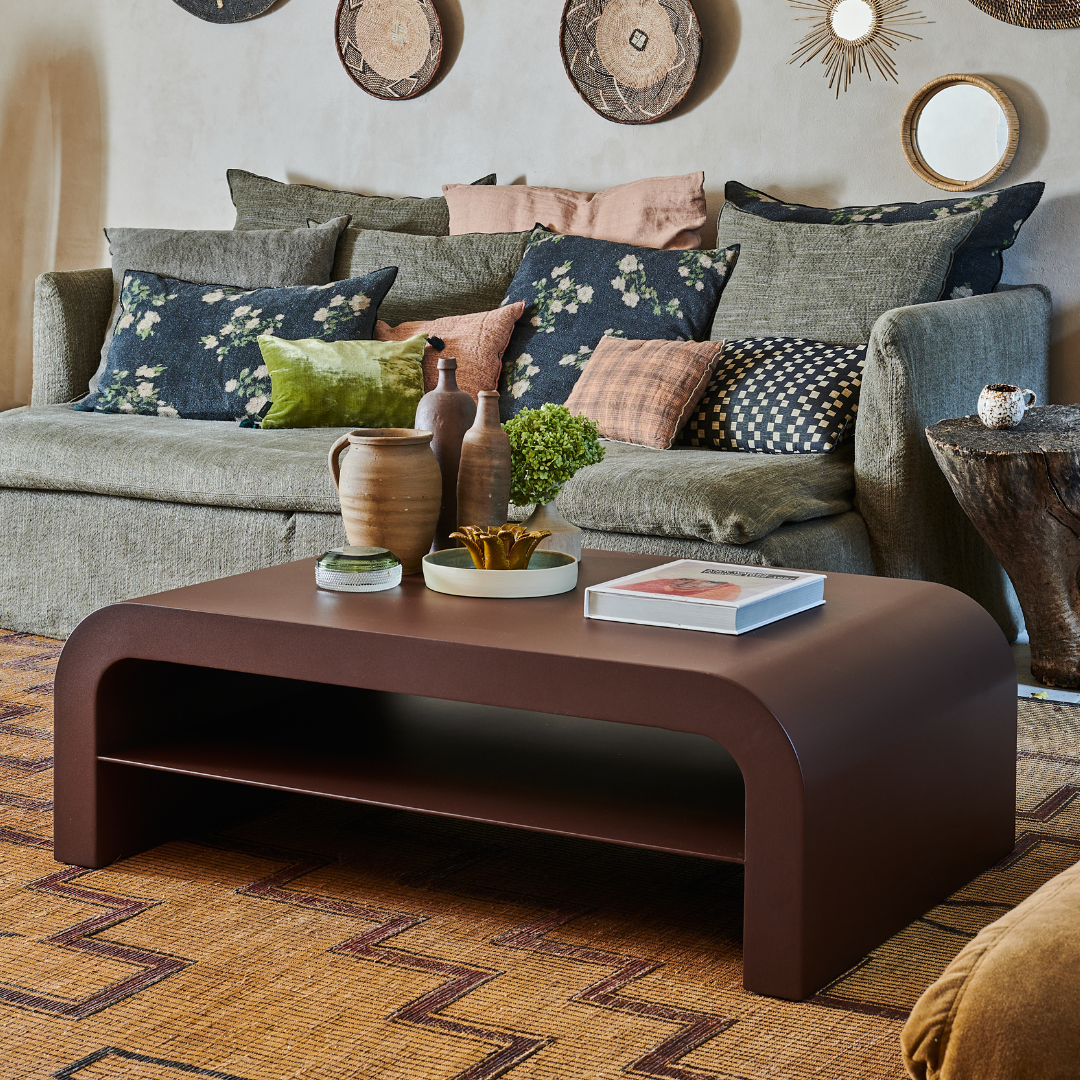 Table basse Gaïa en acier, design épuré avec étagère, mise en scène moderne dans un salon cosy.