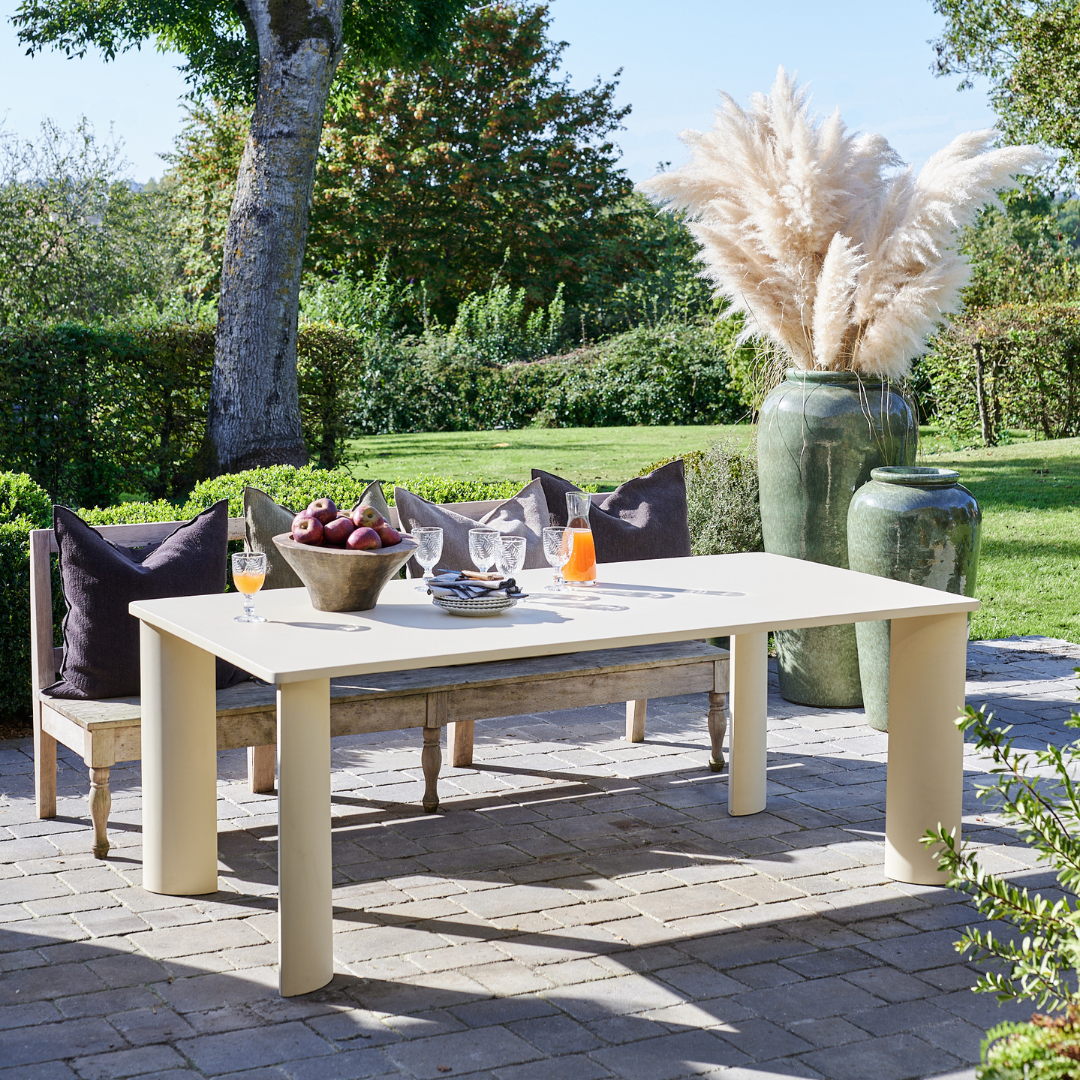 Table de salle à manger Olympe en acier, mise en scène extérieure avec boissons et décorations modernes.