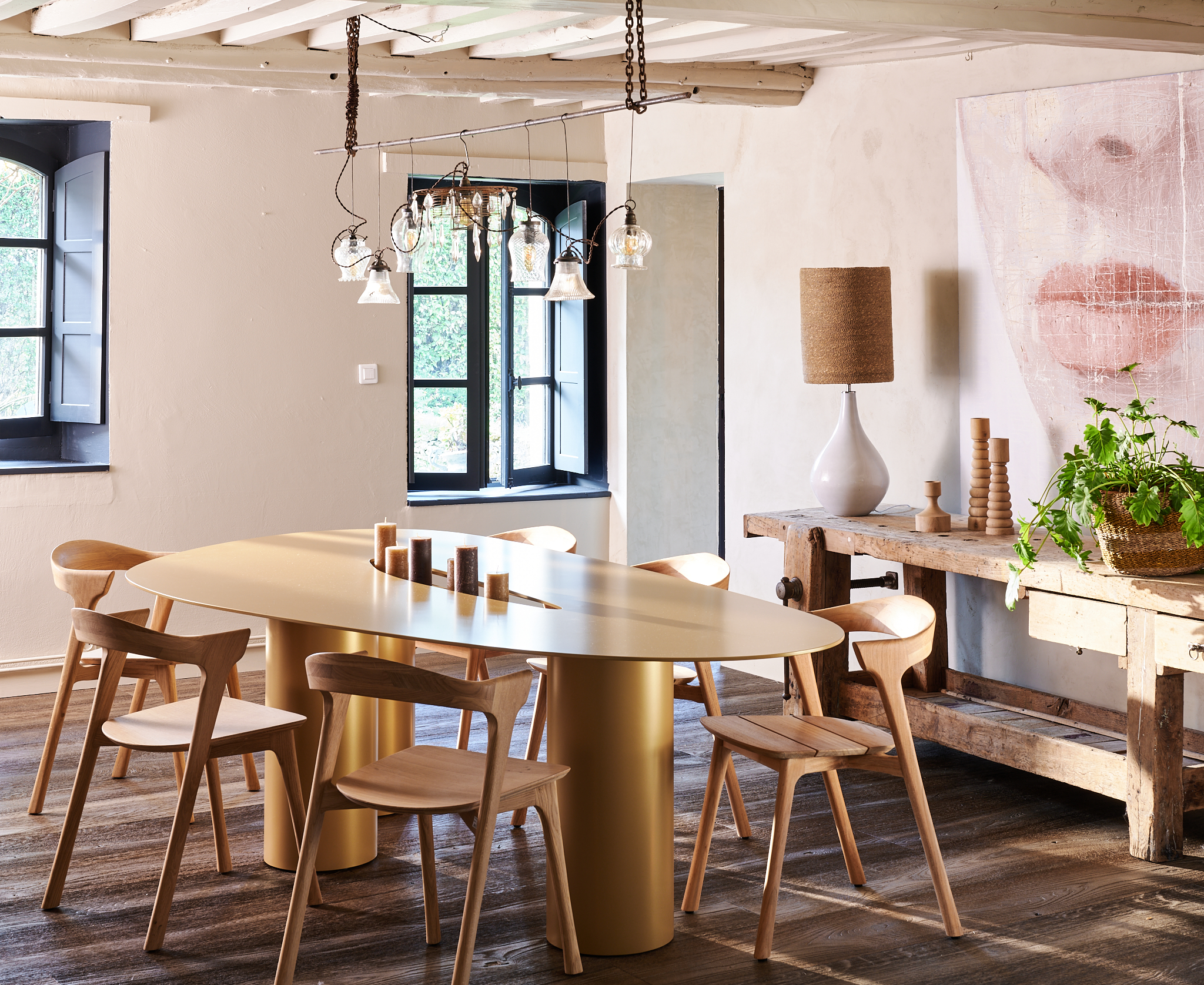Table moderne en acier doré entourée de chaises en bois, dans un intérieur lumineux avec des détails contemporains.