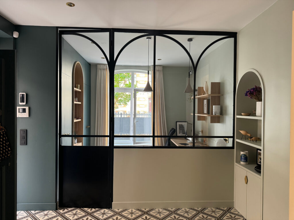 Intérieur moderne montrant une séparation en acier noir, stylisé avec des plantes et des étagères élégantes.